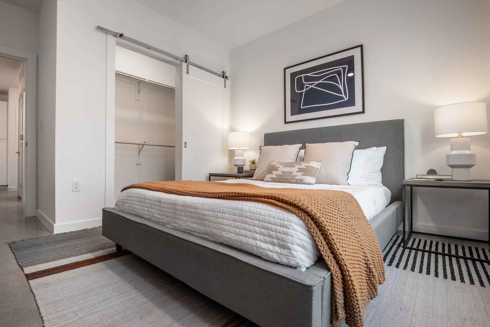 The Artesian at Bee Cave bedroom with sliding barn door closet and upholstered bed