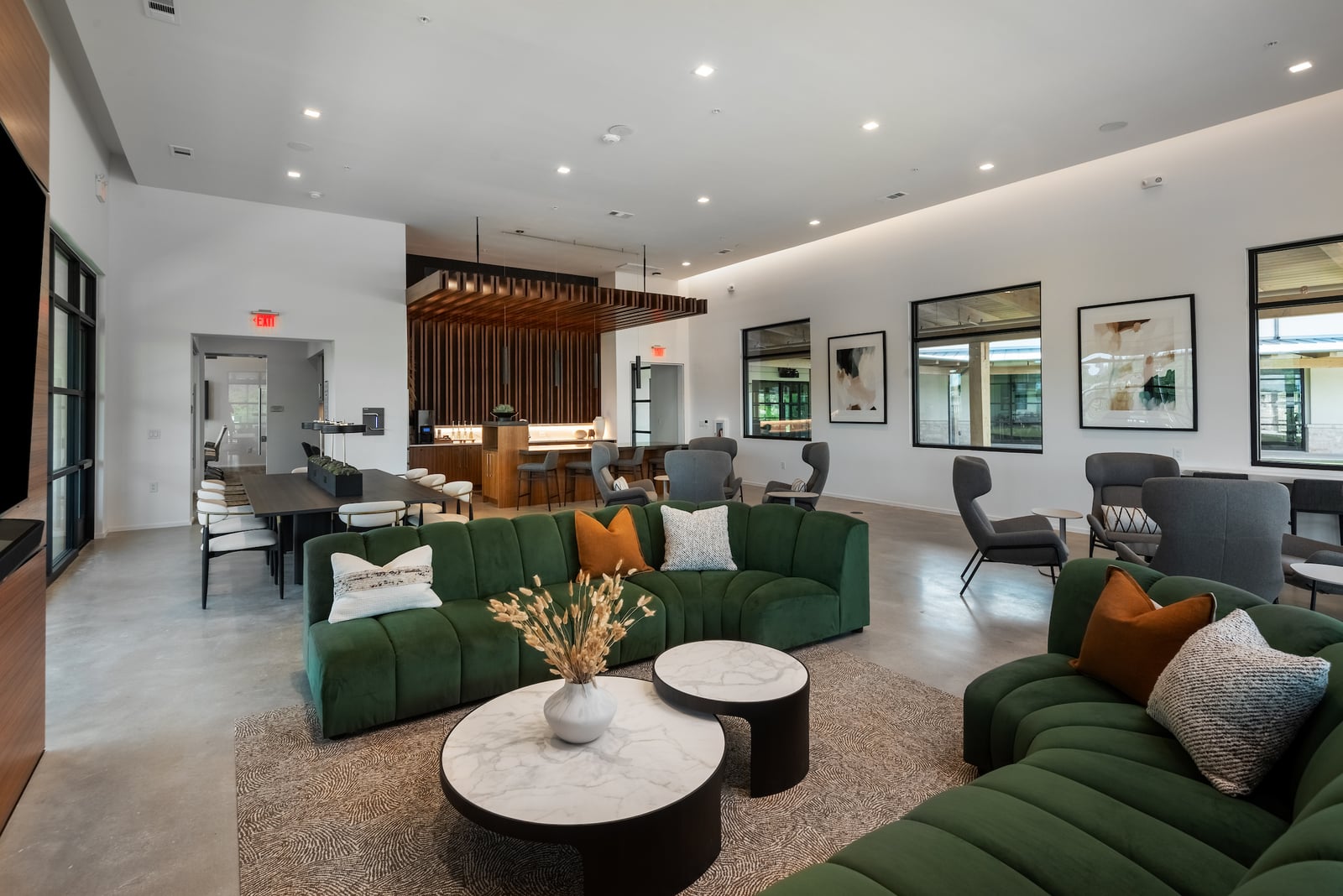 The Artesian at Bee Cave clubhouse lounge with green sectionals and wood slat ceiling
