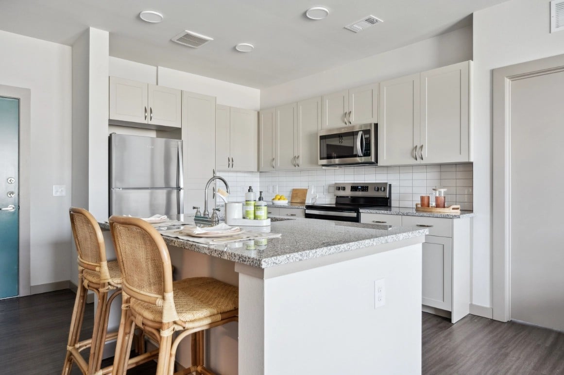 Berry model kitchen with white cabinets, granite counters and peninsula bar seating
