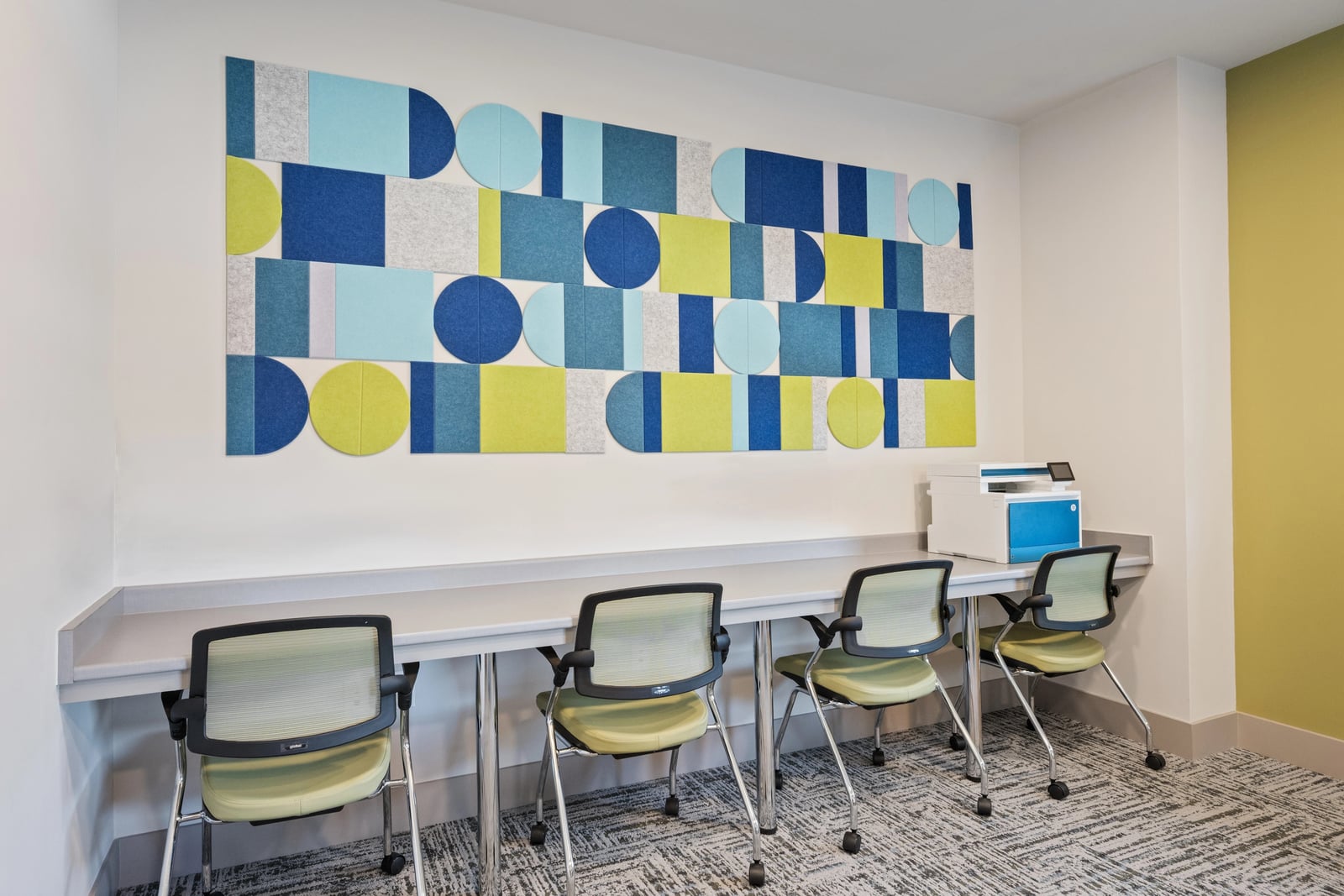 Berry business center with a shared work counter, task chairs and geometric felt wall panels