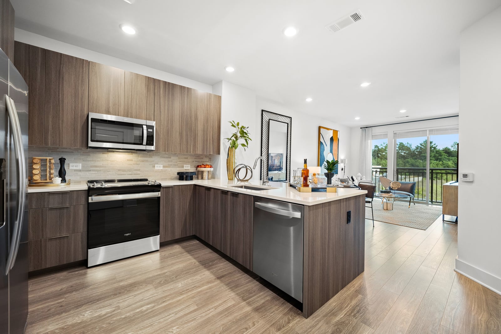 Colony Place kitchen with walnut-tone cabinets, stainless appliances and open living room