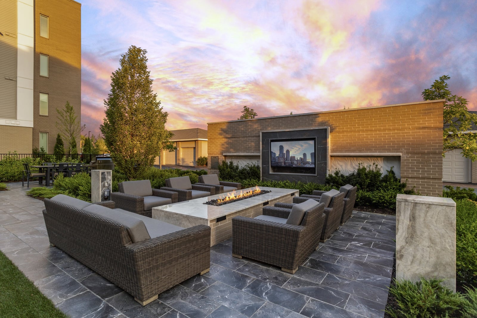 Colony Place outdoor lounge with a gas fire table and a TV wall