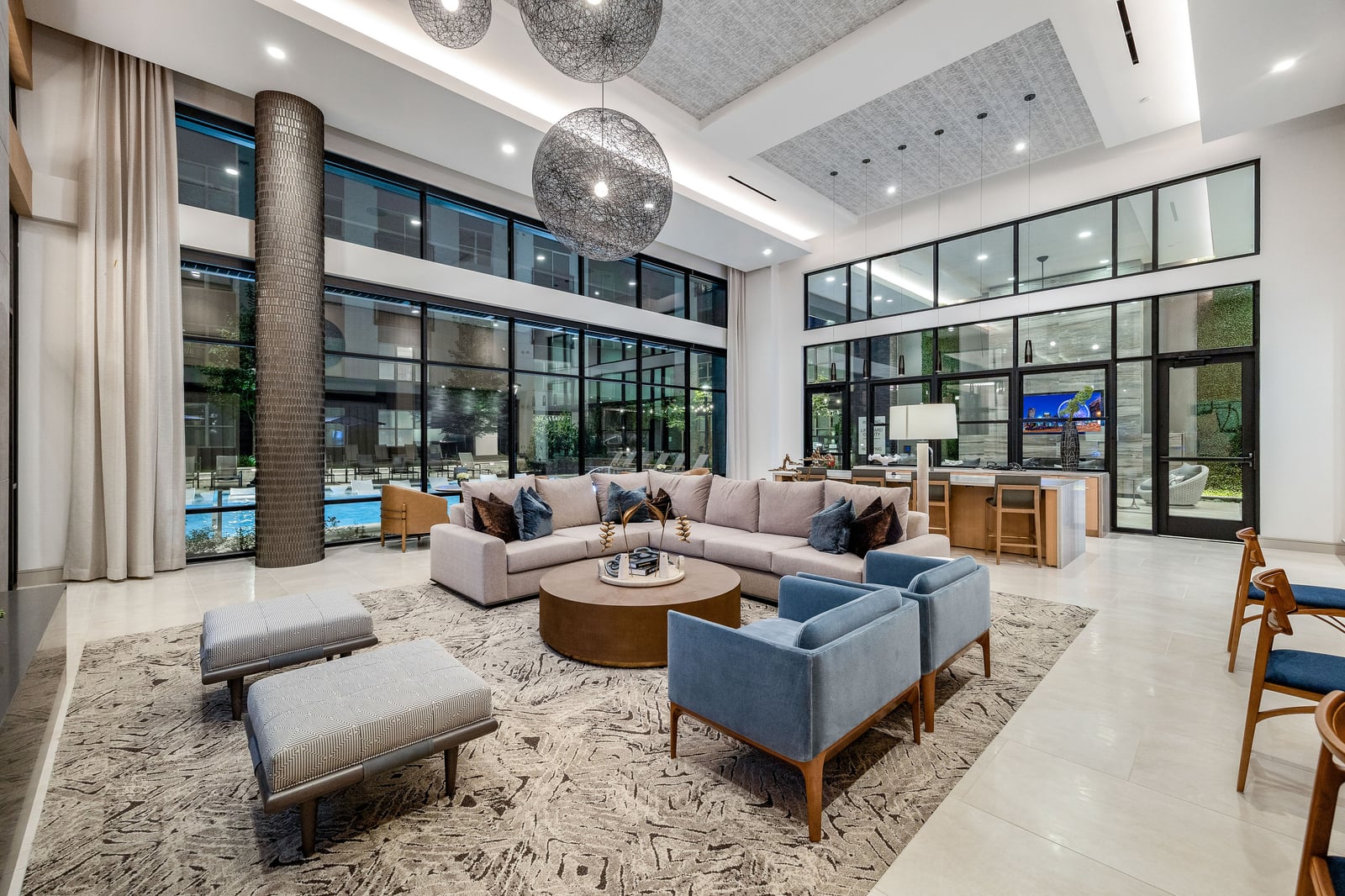 Edgewood double-height resident lounge with sectional and pool view