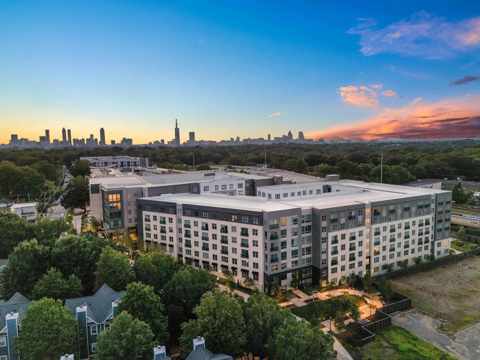 Edgewood mid-rise apartment community aerial view at dusk with the Atlanta skyline behind, Atlanta, GA
