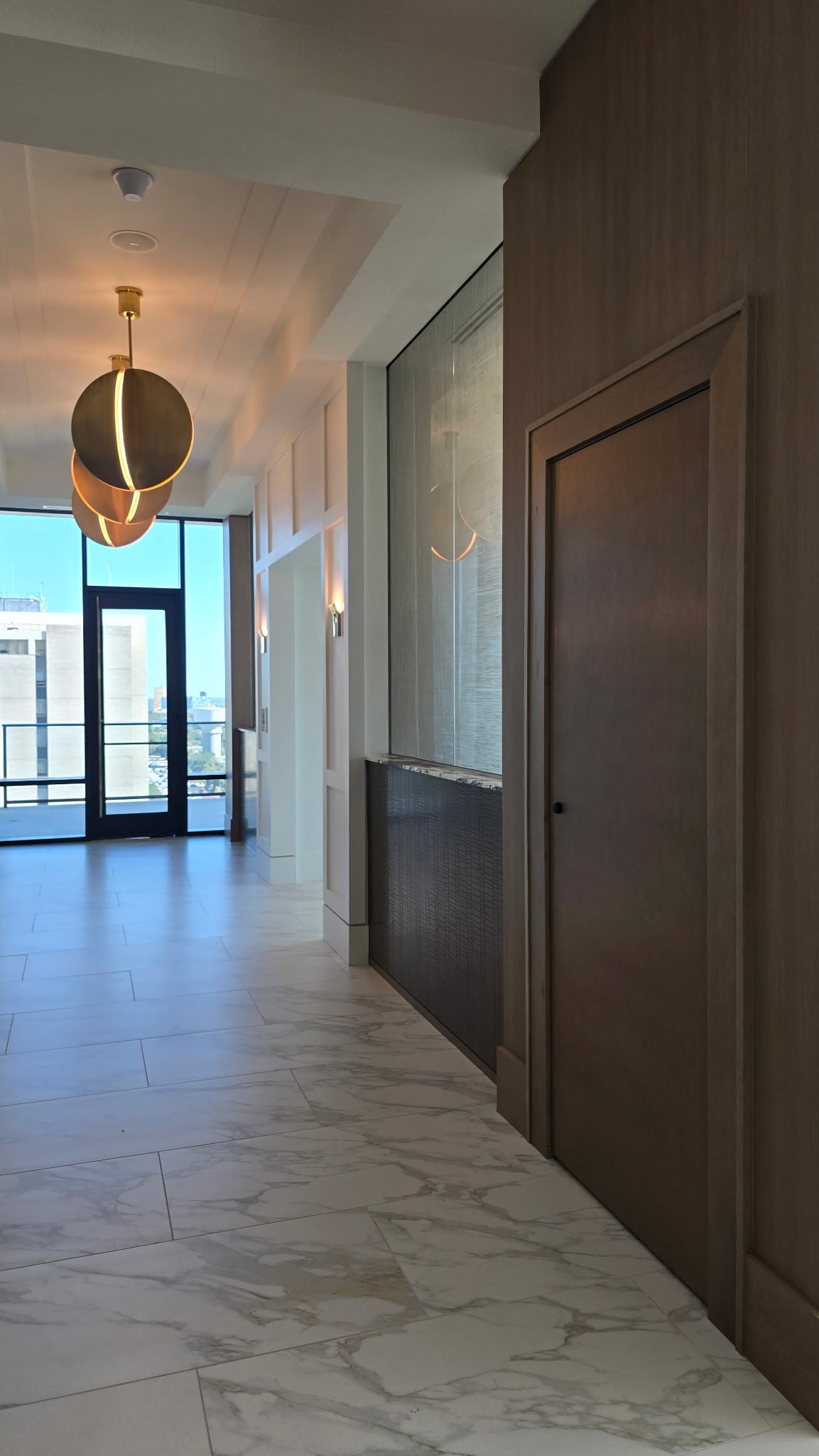 Preston Hollow amenity hallway with brass pendant lights and city views