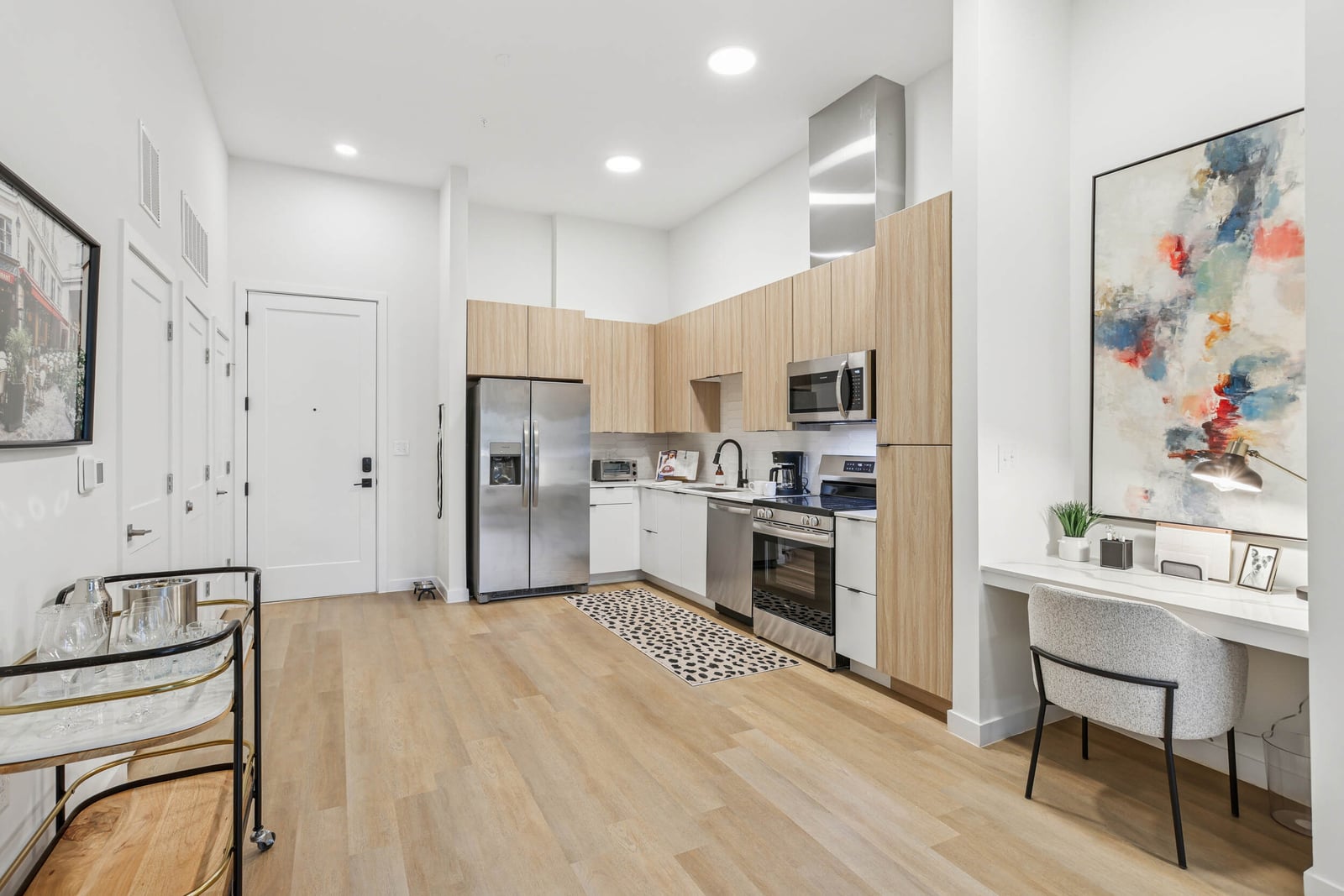 Wellory Living kitchen with light wood cabinets, entry door and built-in desk